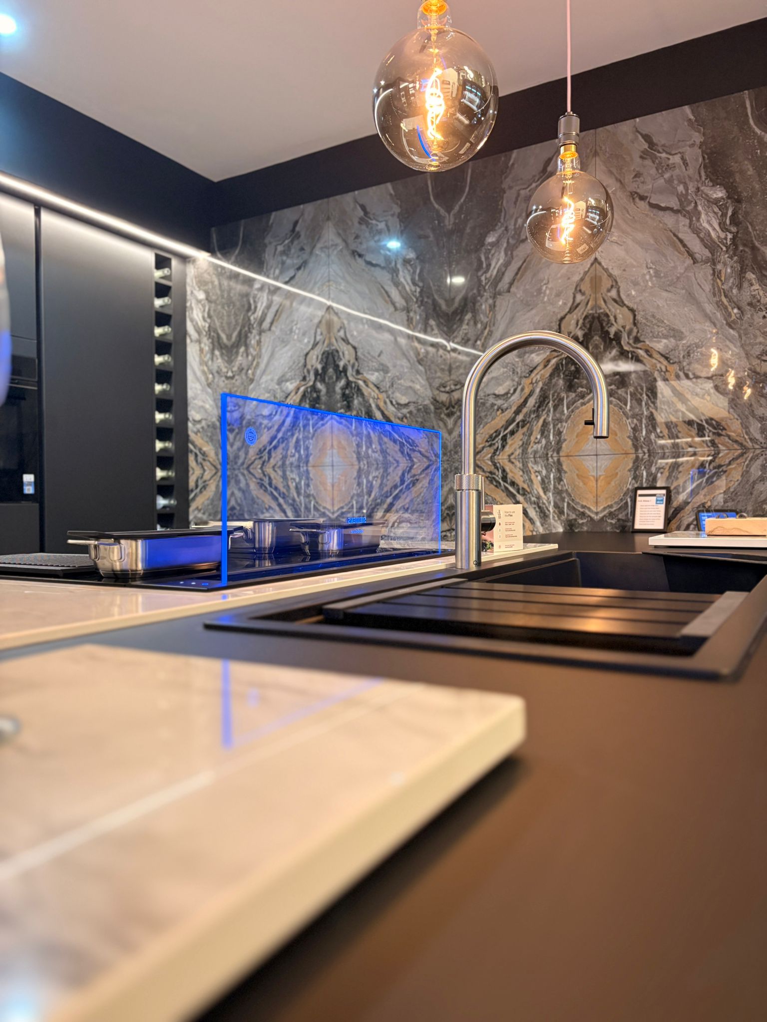 Showroom kitchen with a marble-effect splashback and pendant bulbs