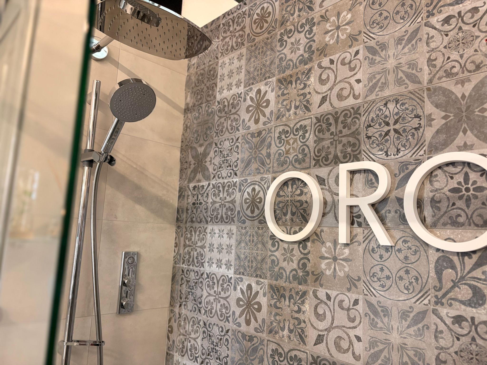Shower with a rainfall head over patterned grey tiles