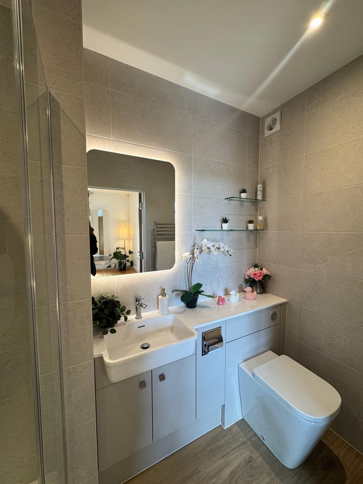 Downstairs toilet with a backlit mirror and white vanity